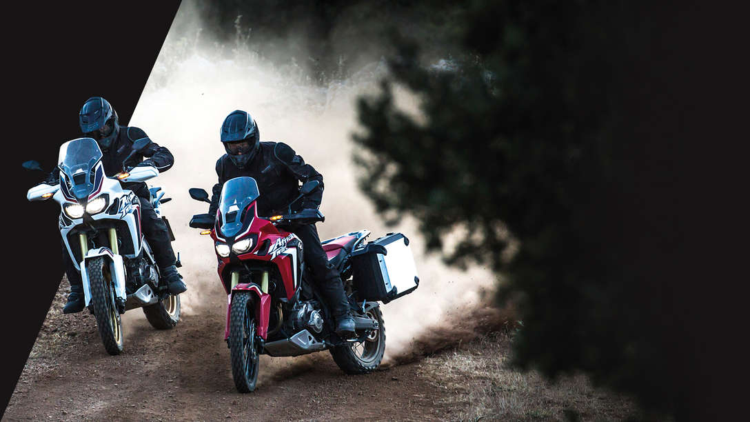 Dos motocicletas Africa Twin circulando por un camino forestal
