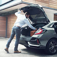 Hombre abriendo el maletero detrás de un Honda Civic 5 puertas