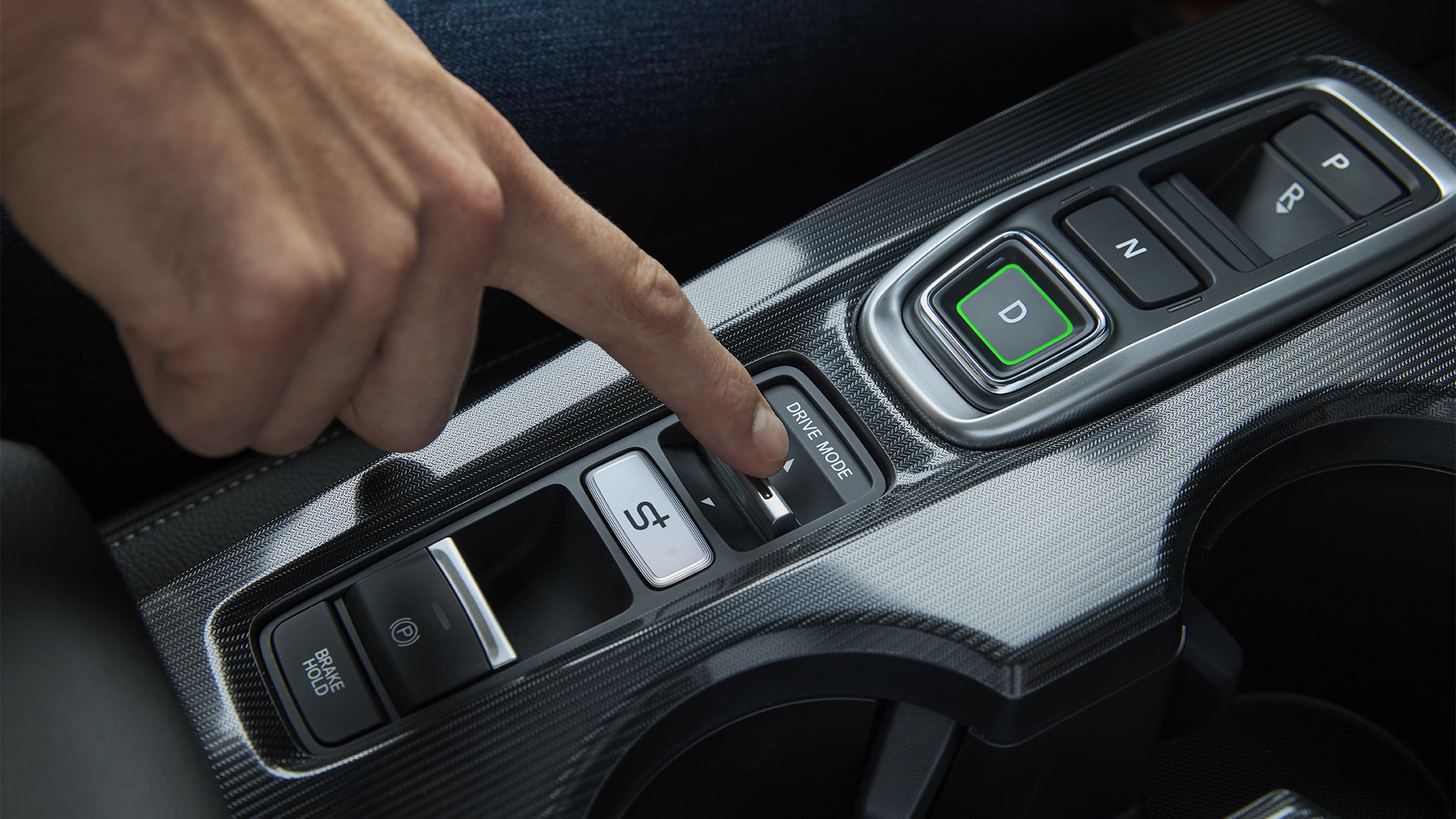 Primer plano de una persona dentro del Civic Hybrid, configurando el modo de conducción del coche.
