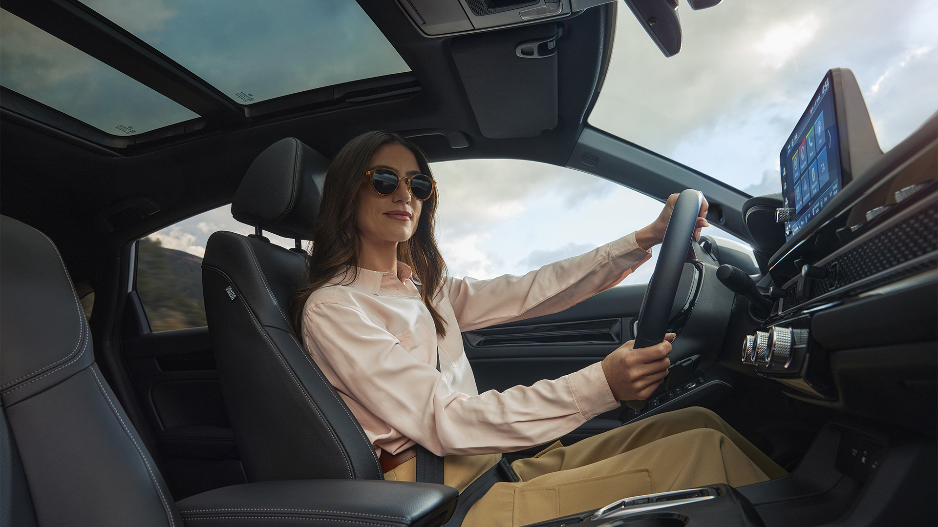 Una mujer con gafas de sol, con las manos en el volante del Civic Hybrid.