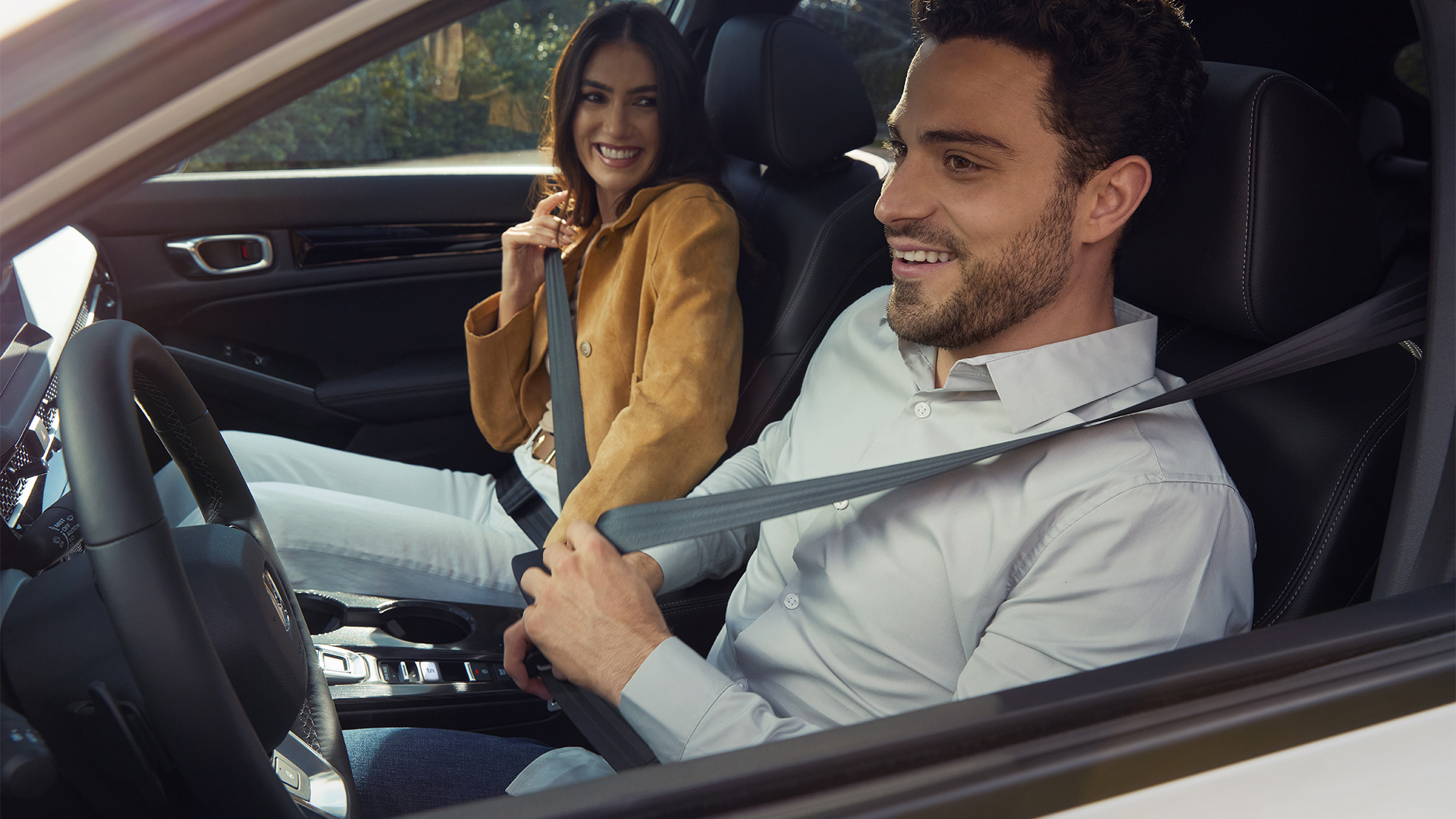 Dos personas abrochándose los cinturones de seguridad dentro del Honda Civic Hybrid.