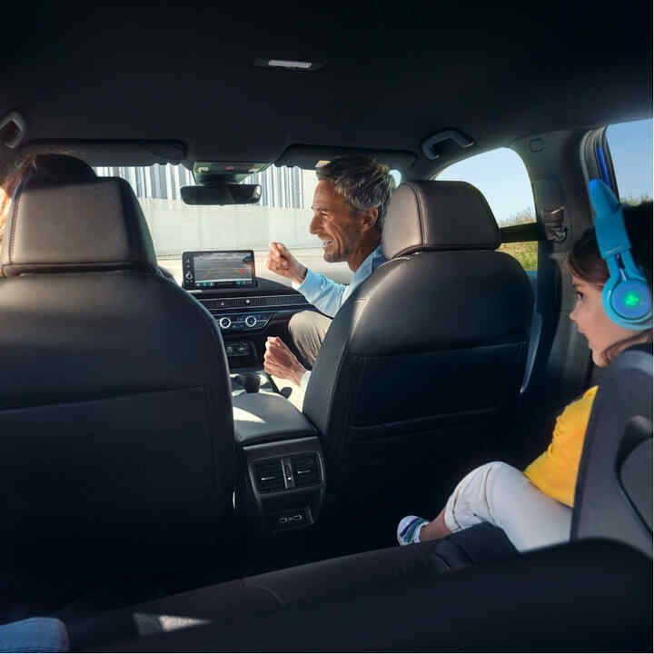 Vista desde los asientos traseros de una familia sentada dentro del coche. 