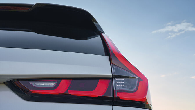 Vista lateral trasera del SUV CR-V Plug-in Hybrid azul en la montaña.