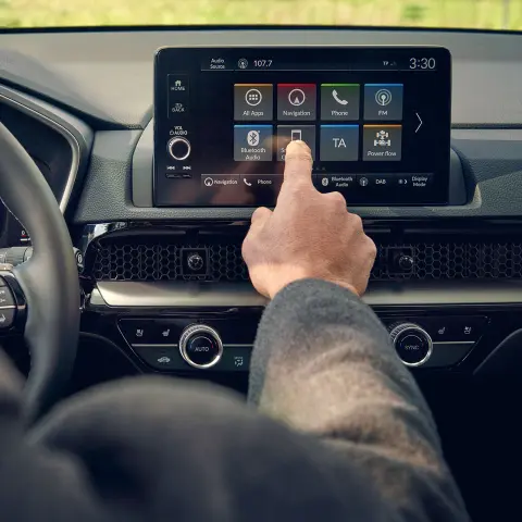 Toma del interior con el conductor usando la pantalla de visualización frontal del SUV CR-V Híbrido en un parque.