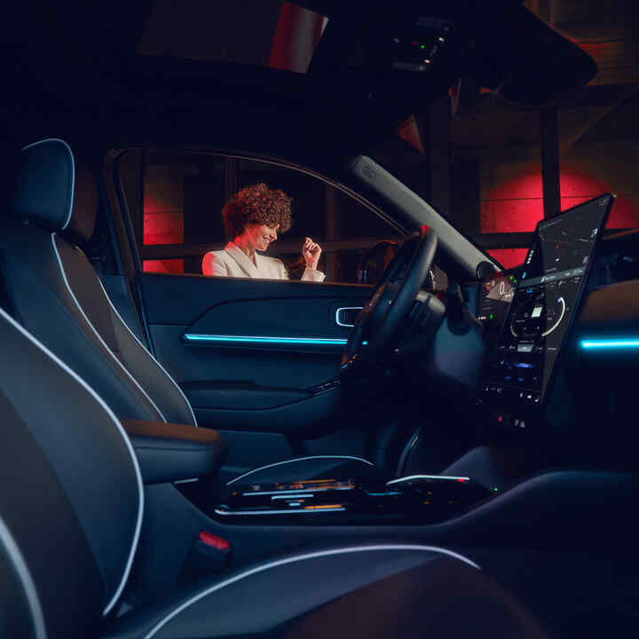 Interior iluminado en el Honda e:Ny1 de noche con modelo junto a la ventanilla.
