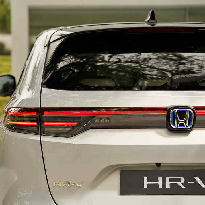 Pareja caminando junto a un HR-V estacionado afuera del edificio. 