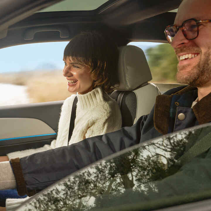 Pareja sonriendo dentro del coche. 