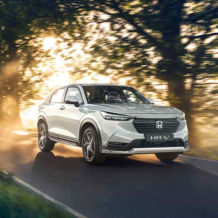 Vista frontal de tres cuartos del Honda HR-V Hybrid circulando por el campo.