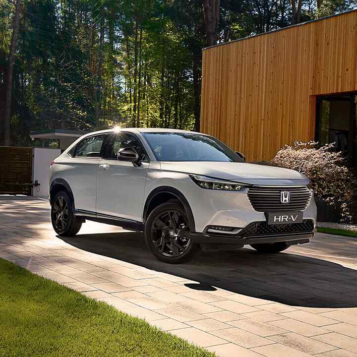 Vista frontal de tres cuartos del Honda HR-V Hybrid estacionado delante de una casa