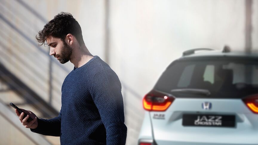 Mujer de pie al lado de un Honda e blanco utilizando la aplicación My Honda Plus