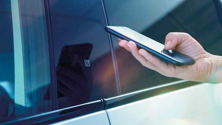 Aplicación My Honda+, primer plano de una persona utilizando un teléfono fuera del vehículo
