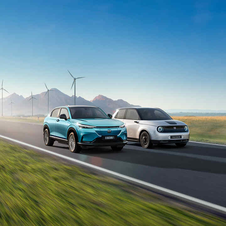 Honda e:Ny1 y Honda e pasando por las inmediaciones de un parque eólico.