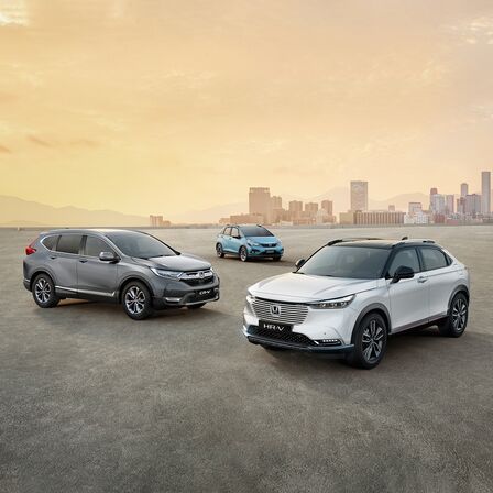 Gama de automóviles Honda híbridos estacionados con paisaje urbano de fondo