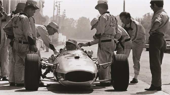 Vista delantera del coche de Fórmula 1 de Honda de los sesenta con el piloto y los ingenieros.