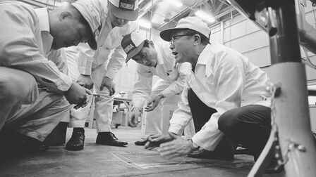 Soichiro Honda y algunos empleados de la fábrica con monos blancos.