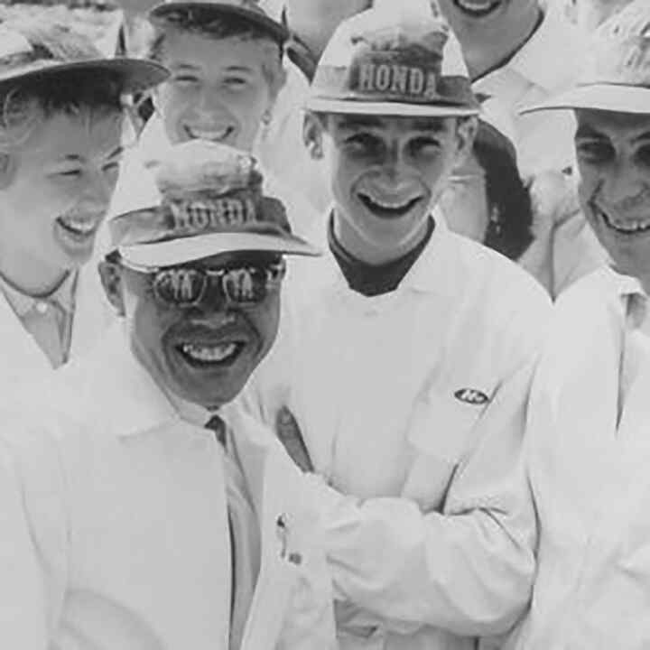 Soichiro Honda y algunos empleados de la fábrica con monos blancos.