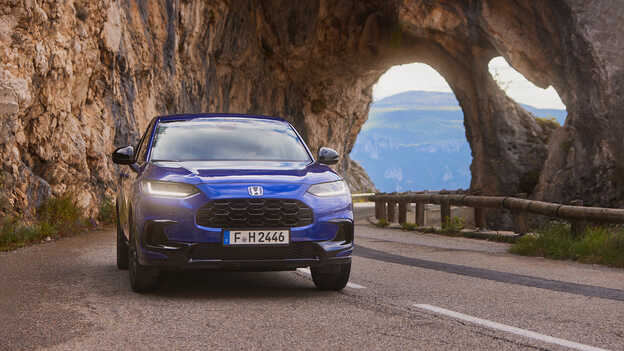 SUV ZR-V Híbrido azul con tren de potencia deportivo circulando por carretera de montaña.