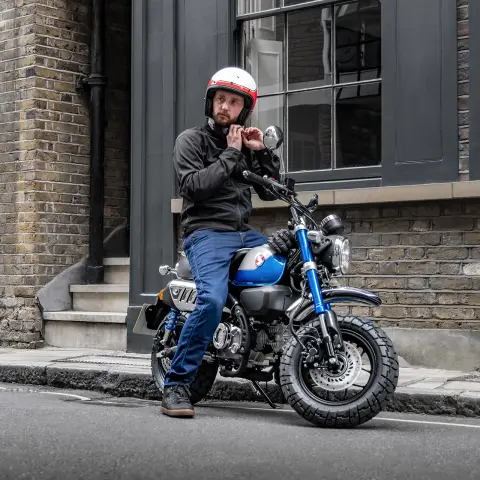 Honda Monkey 125 con conductor aparcada junto a la carretera