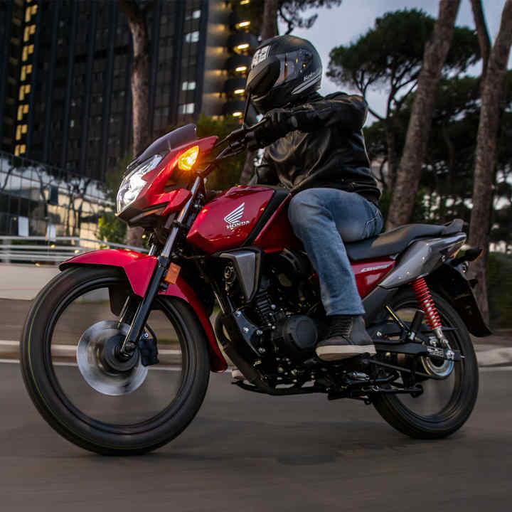 Vista delantera izquierda de tres cuartos de una CB125F roja, en carretera, localización urbana