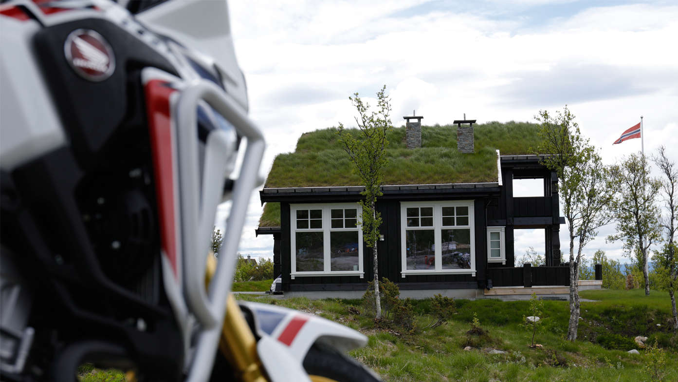 Honda Adventure Roads Nordkapp Dia 1 de Oslo a Fosnavag Africa Twin frente casa con tejado con cesped