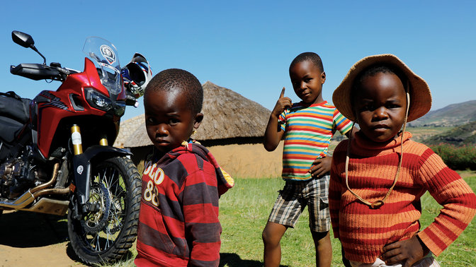 Niños pequeños afuera reunidos alrededor de una CRF1000L Africa Twin