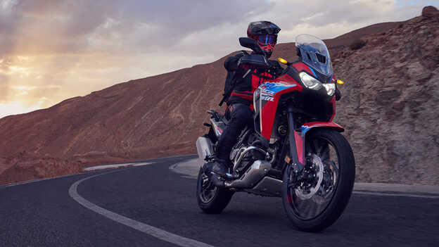 Modelo conduciendo una moto CRF1100L Africa Twin en lugar desértico.