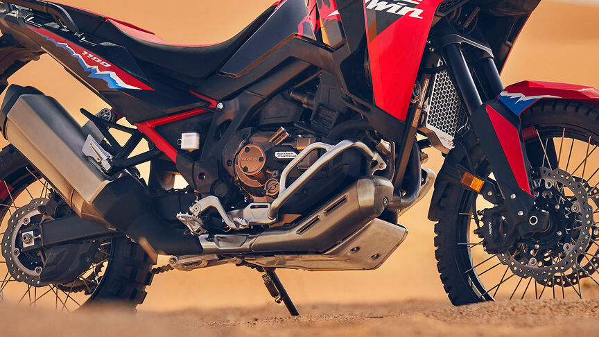 Modelo conduciendo una moto CRF1100L Africa Twin en lugar desértico.