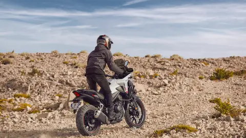 Vista trasera de ¾ de la Honda NX500 circulando fuera de la carretera