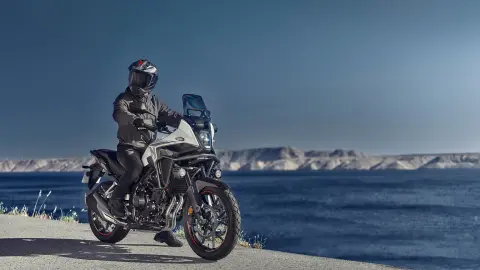 Imagen de la Honda NX500 con el piloto junto a la costa