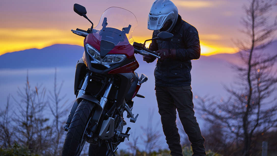 Honda VFR800X Crossrunner aparcada en un paisaje campestre junto al conductor a pie