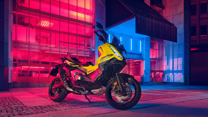 Vista frontal de tres cuartos de la edición especial de la X-ADV parada enfrente de un edificio