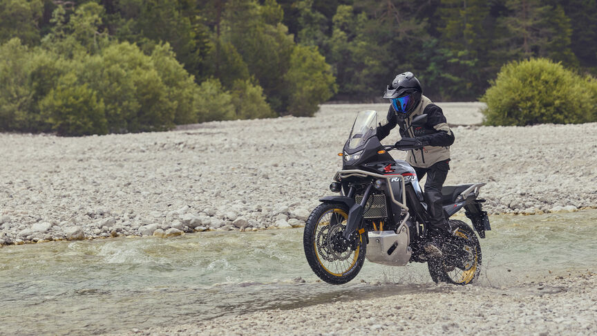 Modelo circulando con la motocicleta XL750 Transalp en una zona boscosa.