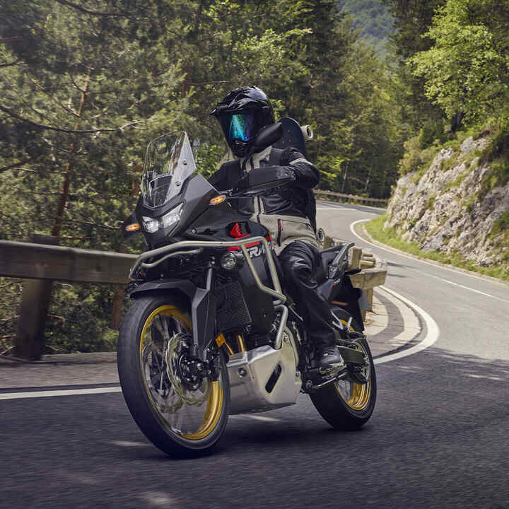 Modelo conduciendo una motocicleta XL750 Transalp en un entorno montañoso.
