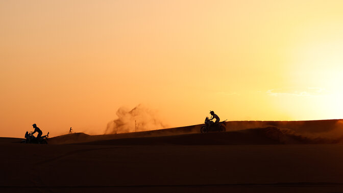 Pilotos de Honda Adventure Roads en el desierto al atardecer.