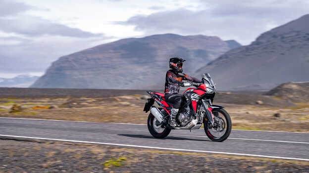 Vista de tres cuartos delantera de la Africa Twin con motorista en carretera