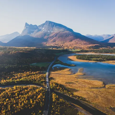 Clásico paisaje montañoso escandinavo de Noruega en verano, con carretera, montañas y fiordos, cielo azul, norte de Noruega, condado de Finnmark, tomada desde un dron