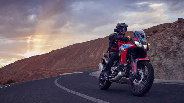 Vista de tres cuartos delantera de la Africa Twin con motorista en carretera