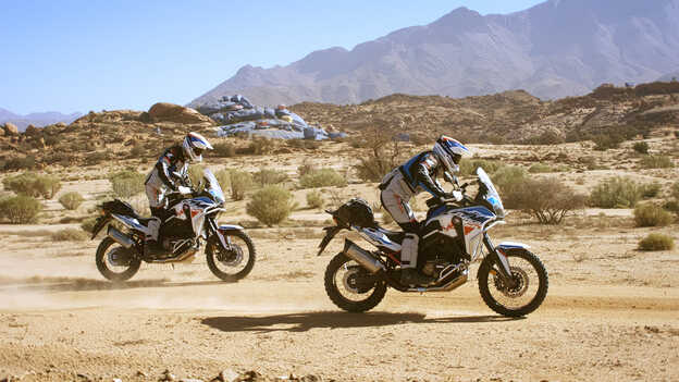 Dos pilotos de Honda Adventure Roads en Marruecos, con las impresionantes rocas al fondo