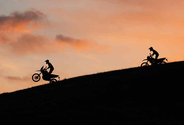 Dos motos Honda de la serie 300 bajando una colina a la puesta del sol