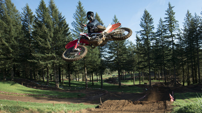 CRF450R saltando con conductor. Localización en una pista de dirt.