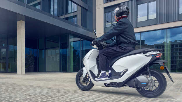 Modelo conduciendo una motocicleta Honda CUV e demostrando la asistencia para marcha atrás fácil.