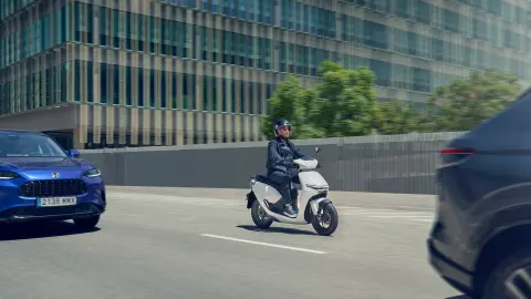 Conductor conduciendo una motocicleta Honda CUV e en una zona urbana.