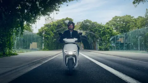 Vista delantera de un modelo conduciendo una motocicleta Honda CUV e en un entorno urbano.