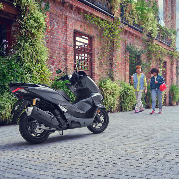 Modelos caminando hacia la motocicleta PCX125.