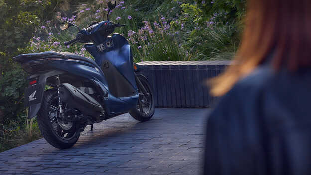 Vista trasera de la Honda SH350i en un jardín. 