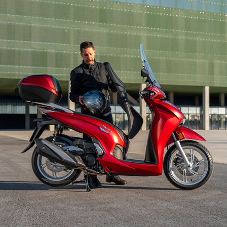 Honda SH350i, hombre de pie junto a scooter, vista trasera, moto roja