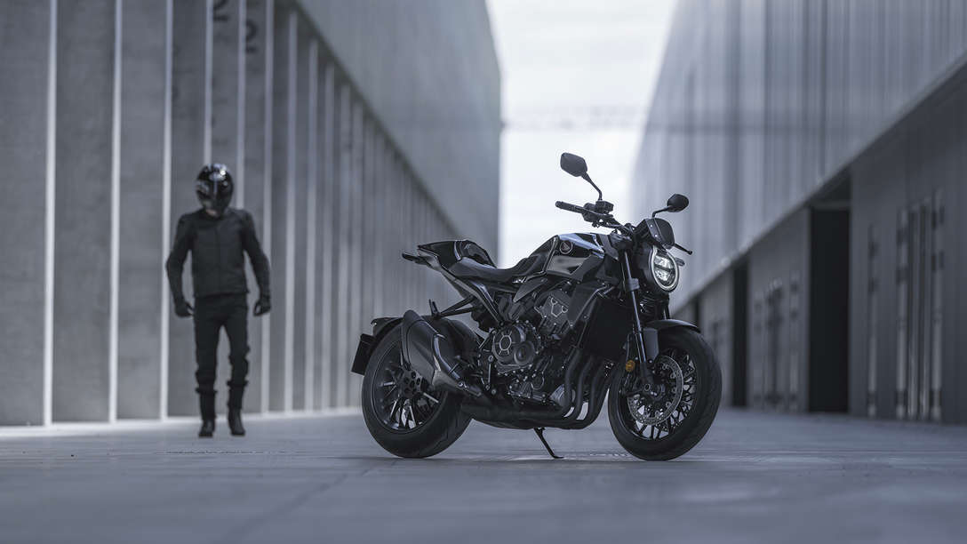 Honda CB1000R Black Edition - hombre de pie junto a la moto en la calle entre edificios