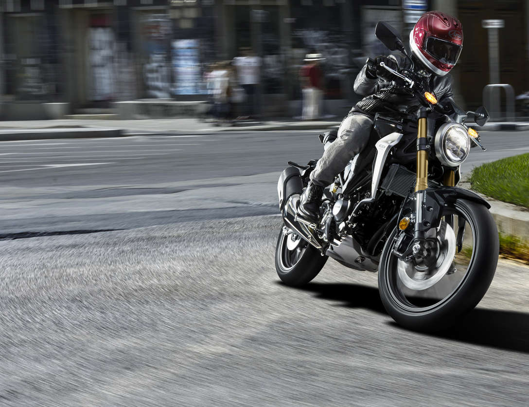 Vista delantera de tres cuartos de la Honda CB300R Neo Sports Café, circulando por la calle.