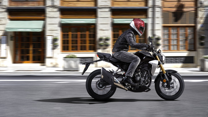 Vista lateral de la nueva Honda CB300R Neo Sports Café conducida por la carretera.