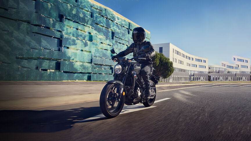 Vista frontal de tres cuartos de la Honda CB300R observada por una mujer en un estudio.